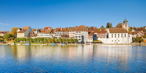View from the banks of the Rhine over the Rhine towards the old town of Eglisau with reflection on the river water