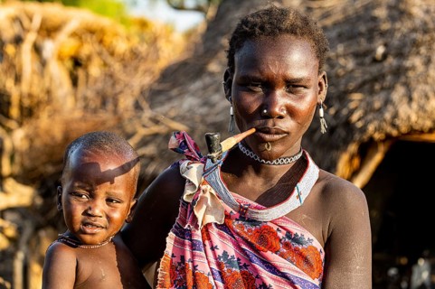 Woman from the Toposa tribe with her baby smoking a pipe