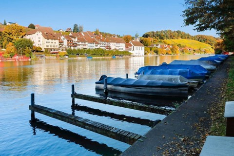 View from the banks of the Rhine over the Rhine towards the old town of Eglisau with reflection on the river water