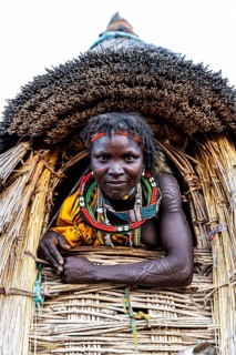 Traditional dressed girl from the Toposa tribe sitting in a grain storage
