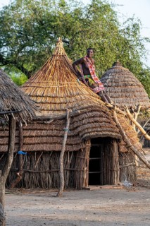 Woman repairing a roof of a traditional build hut of the Toposa tribe