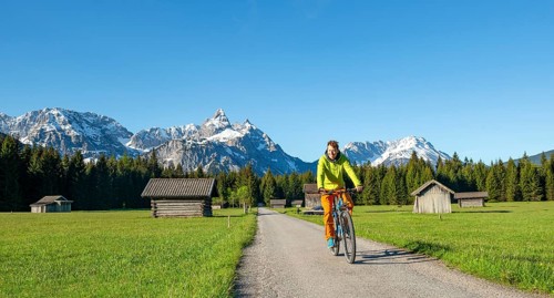 Mountain biker on road through meadow with hay barns