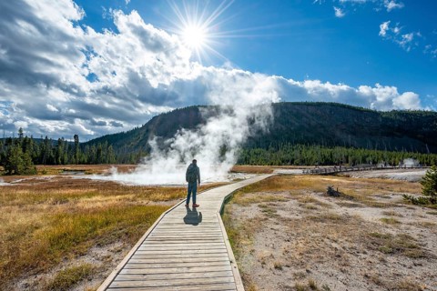 Tourist on a logging road in front of steaming hot spring