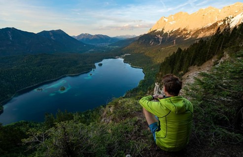 Young man looking over the Eibsee lake at sunset
