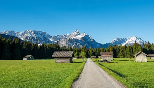 Road through meadow with hay barns