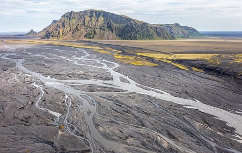 River with fanned out branches through black lava sand