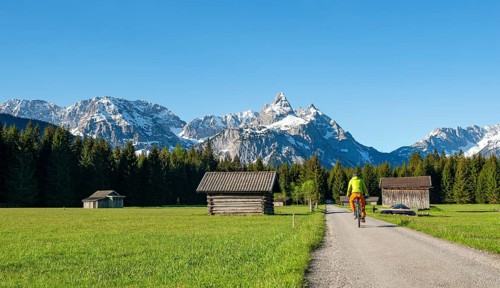 Mountain biker on road through meadow with hay barns