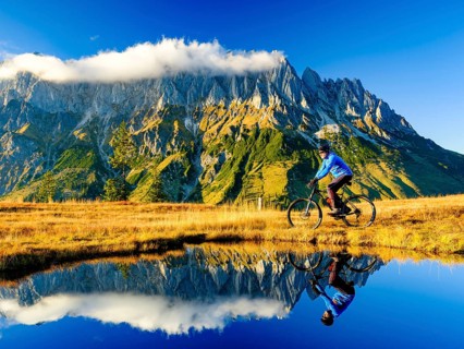 Mountain biker in front of mountain scenery reflected in a mountain lake