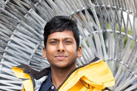 Young man with yellow jacket in front of a wicker chair