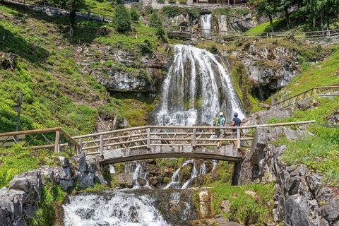Hikers at the waterfall in front of the Saint Beatus Caves