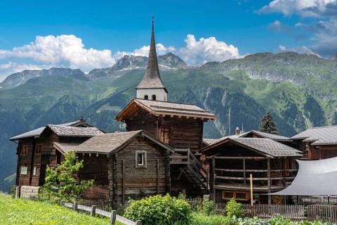 Historic village centre with wooden Valais houses and tower of the Seven Joys of Mary parish church