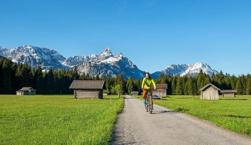 Mountain biker on road through meadow with hay barns
