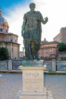 Life-size statue of Julius Caesar on marble plinth next to Forum of Caesar