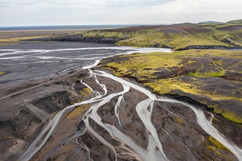 River with fanned out branches through black lava sand