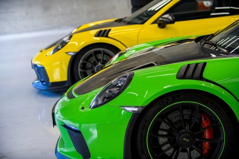 Side view of front with round headlights and rim of Porsche 911 GT3 RS race car in pitbox