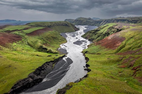 River with fanned out branches through black lava sand