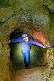 Climber with helmet and headlamp in rock tunnel