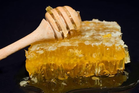 Fresh honeycomb with blossom honey and wooden honey spoon