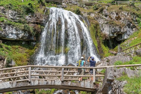 Hikers at the waterfall in front of the Saint Beatus Caves