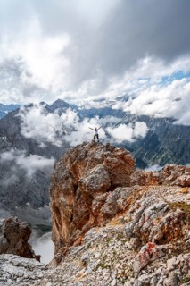 Hiker on a rock stretches arms in the air