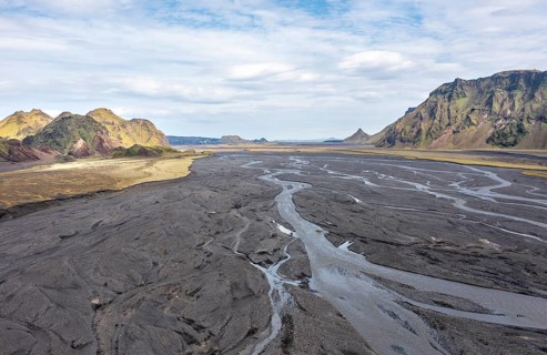 River with fanned out branches through black lava sand