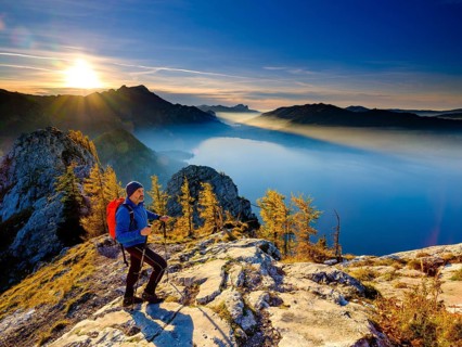 Mountaineer climbing the large Schoberstein in the evening light with view of Attersee and Mondsee