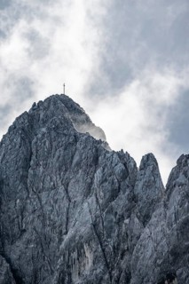 Rocky summit with summit cross between clouds