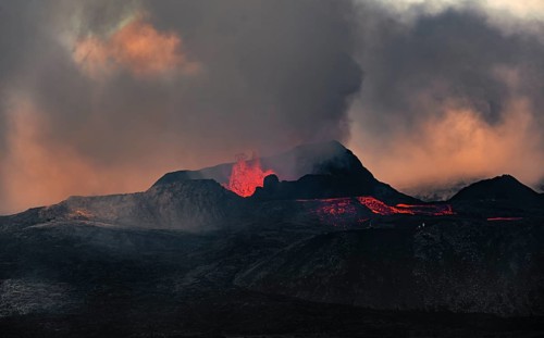 Erupting volcano with lava fountains and lava field