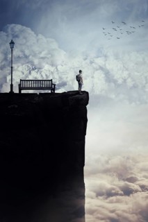 Inspirational imaginary view as a young boy with a bag in his back stand on the peak of a cliff above clouds