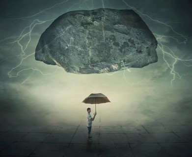 Surrealistic image as a man stand in a foggy street under a huge levitating rock