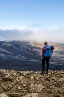 Tourist looking at erupting volcano with lava fountains and lava field