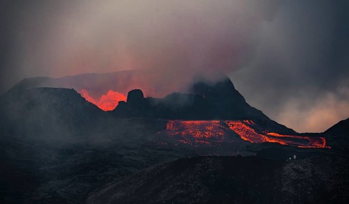 Erupting volcano with lava fountains and lava field