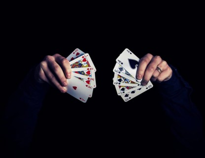 Man's hands holding five playing cards each over