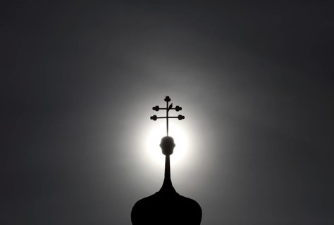 Double cross with dove on a church tower in backlight