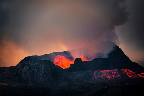 Erupting volcano with lava fountains and lava field