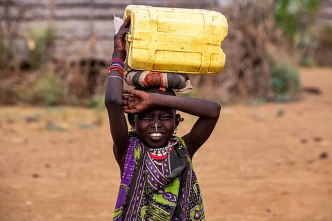 Traditional dressed girl carrying a water container