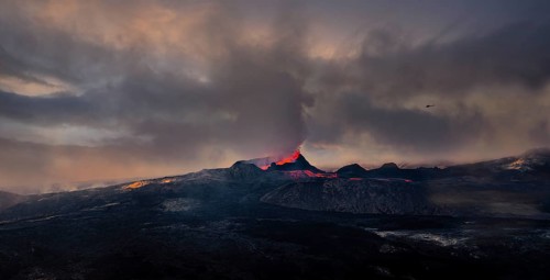 Erupting volcano with lava fountains and lava field