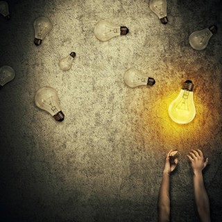 Abstract idea concept as human hands stretched out and juggling with a lot of lightbulbs