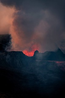 Erupting volcano with lava fountains and lava field