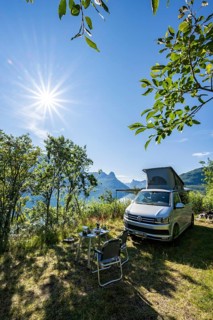 Camper standing by fjord with view of mountains