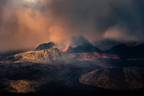 Erupting volcano with lava fountains and lava field