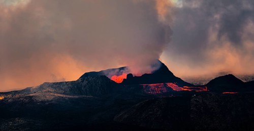 Erupting volcano with lava fountains and lava field