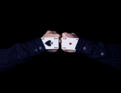 Two fists with hearts and spades aces against each other