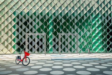 Red rental bike standing in front of the glass facade of the Futurium Museum on Kapelle Ufer