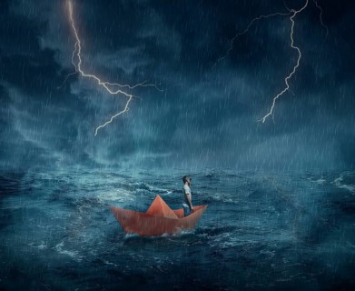Young boy in a orange paper boat sail lost in the ocean