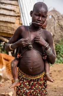 Scar face and body as a mark of beauty woman from the Jiye tribe sitting in her hut