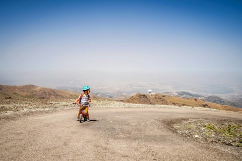 Small boy riding uphill on his first bicycle in Sierra Nevada mountains