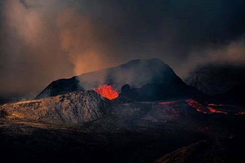 Erupting volcano with lava fountains and lava field