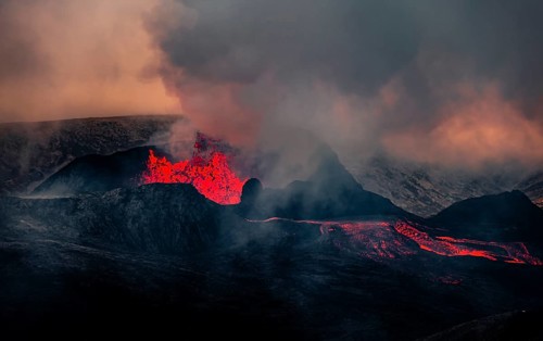Erupting volcano with lava fountains and lava field