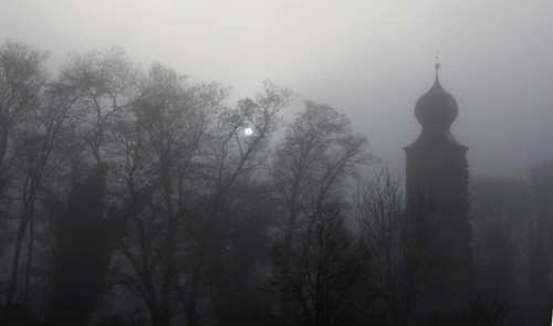 Historic water tower and bare trees in the mist